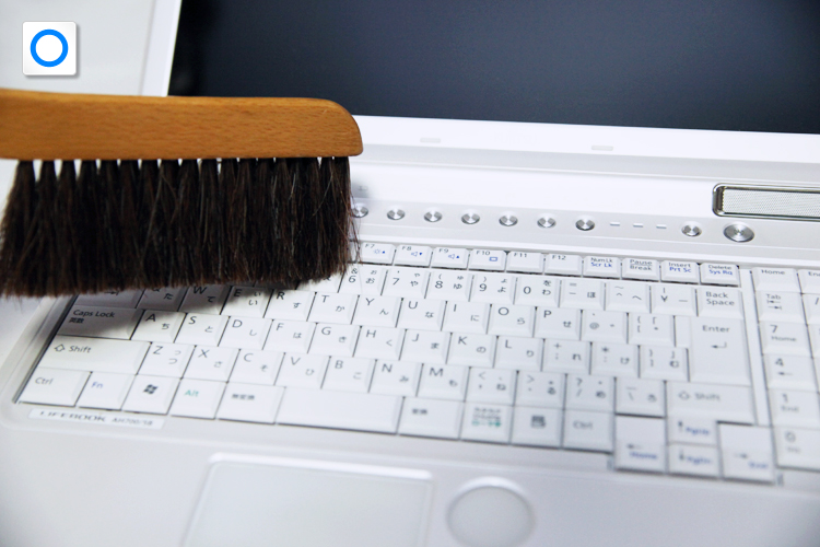 キーのすき間にハケの先を入れて、ホコリをかき出しているイメージ画像